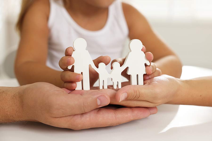 Sozialpädagogische Familienbegleitung (SPF) in Bern und Umgebung Die Hände von 2 Erwachsenen und ein kleines Mädchen halten eine weisse Figurengruppe, die eine familie symbolisiert